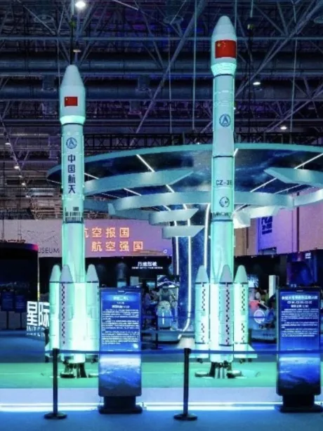 Two full-size Chinese carrier rocket models standing in a blue-lit aerospace exhibition hall.