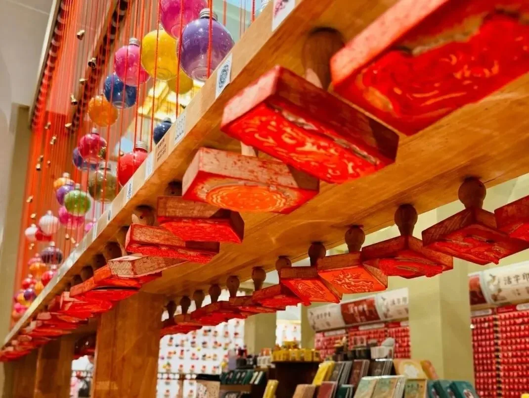 Rows of red-inked wooden seal blocks on tiered racks, coloured glass baubles hanging behind