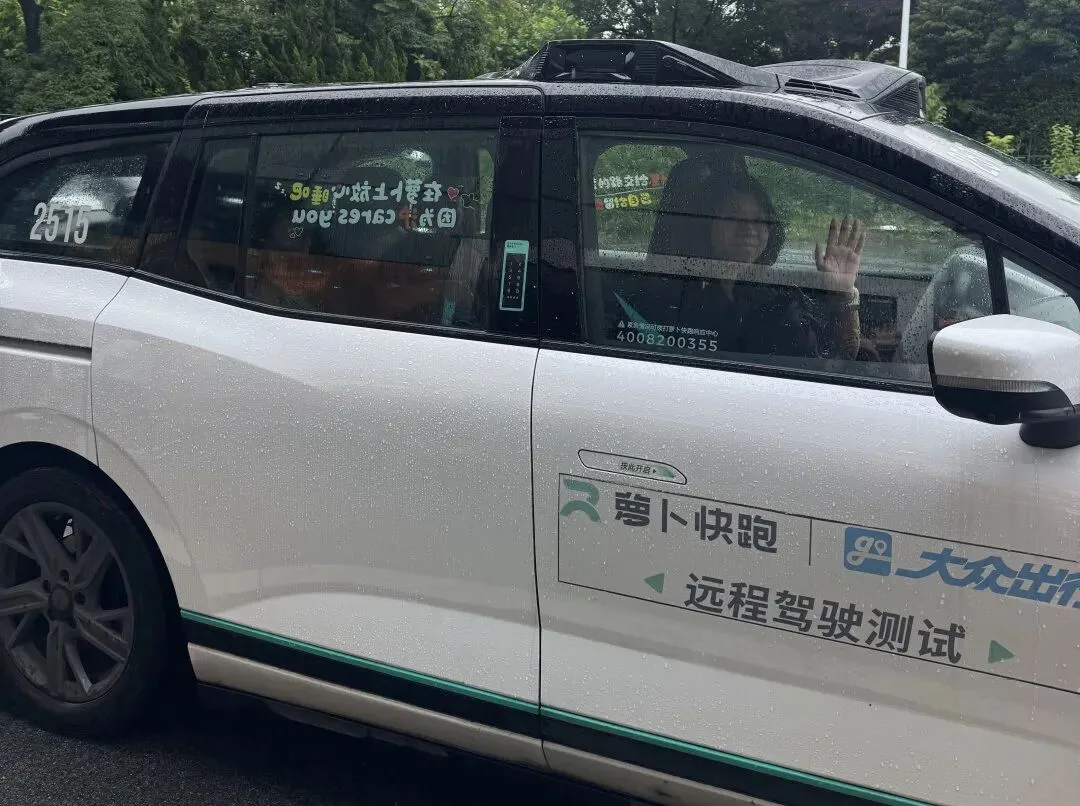 A passenger waves from an Apollo Go robotaxi marked for remote-driving tests