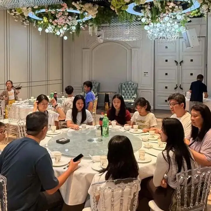 Campers and families share a meal at round tables beneath floral chandeliers