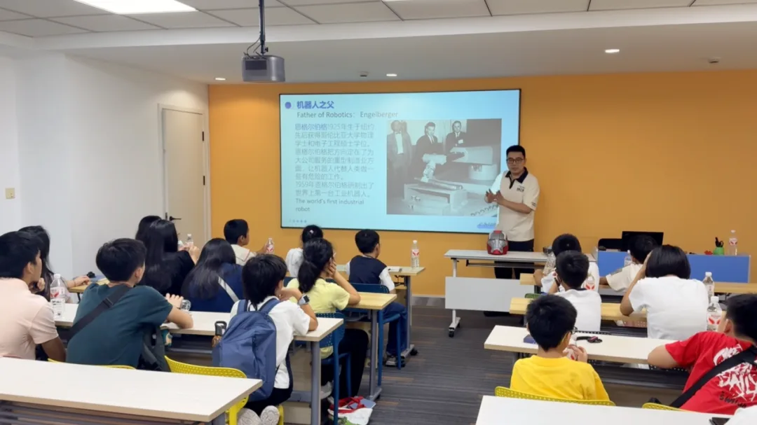 A lecturer presents a slide titled Father of Robotics: Engelberger to seated children