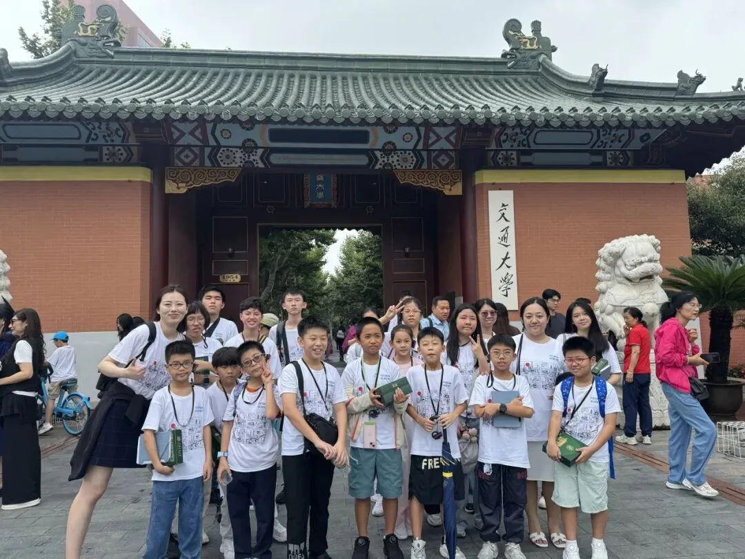 The group poses at Shanghai Jiao Tong University's traditional tiled gate beside a stone lion