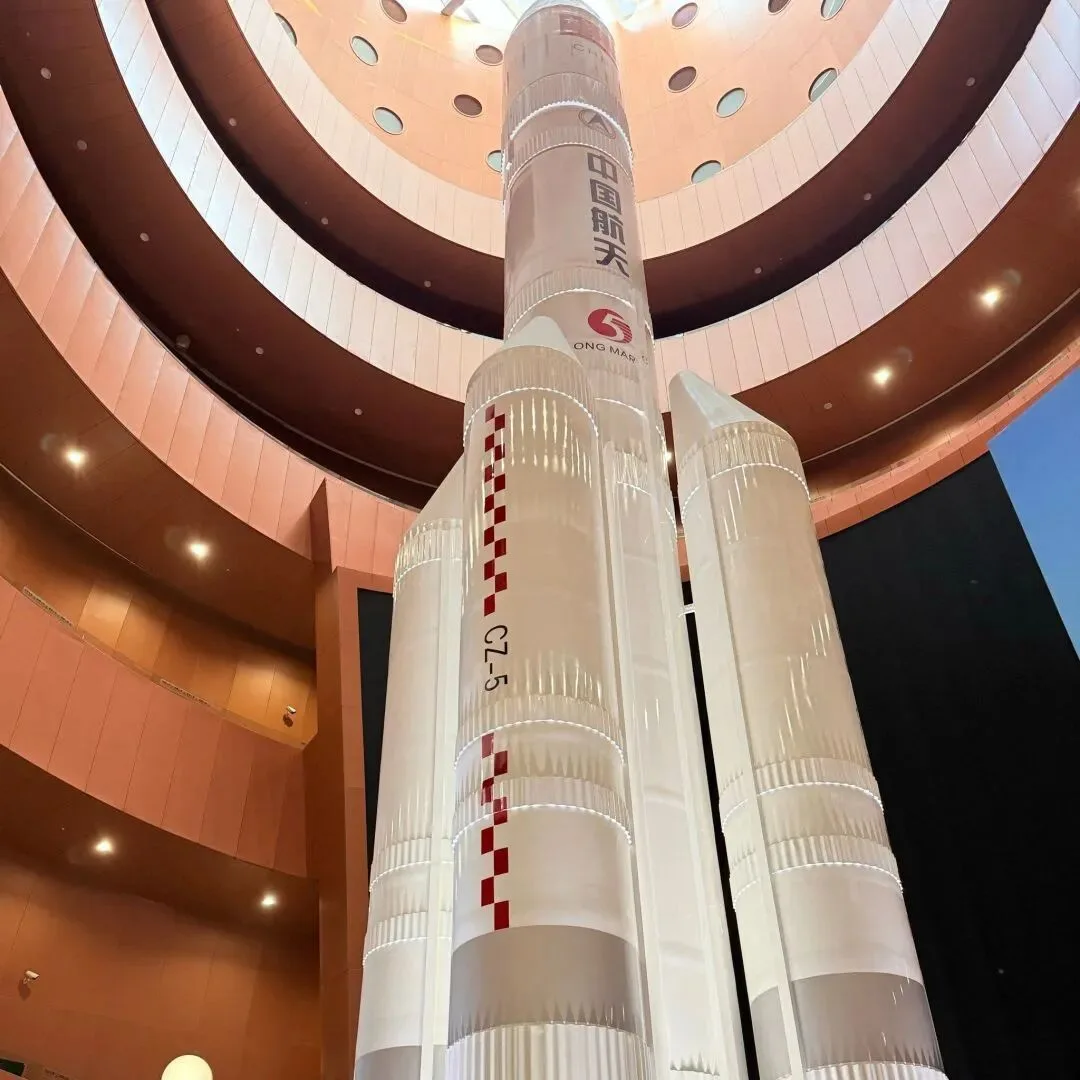 Full-scale Long March 5 carrier rocket model rising through the atrium of a space exhibition hall.