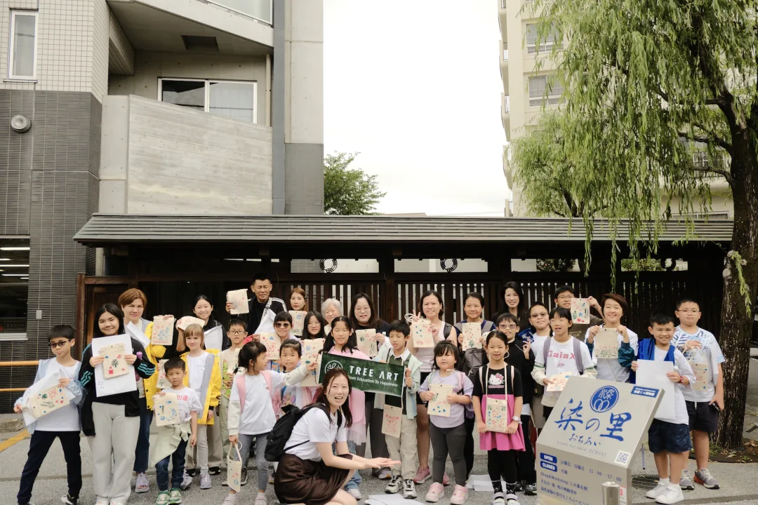 The group holding their finished hand-dyed tote bags outside the dyeing workshop