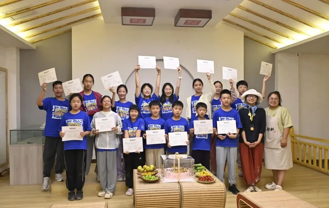 Children in blue camp shirts holding up certificates with two instructors