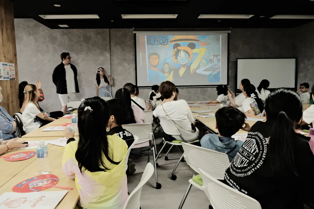 Students in a classroom watching an anime scene projected on screen