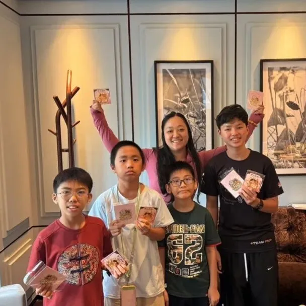 Boys and their instructor hold up souvenir packets together in a hotel lounge
